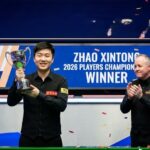Snooker champion Zhao Xintong intensely lining up a shot on the billiard table during a professional match.