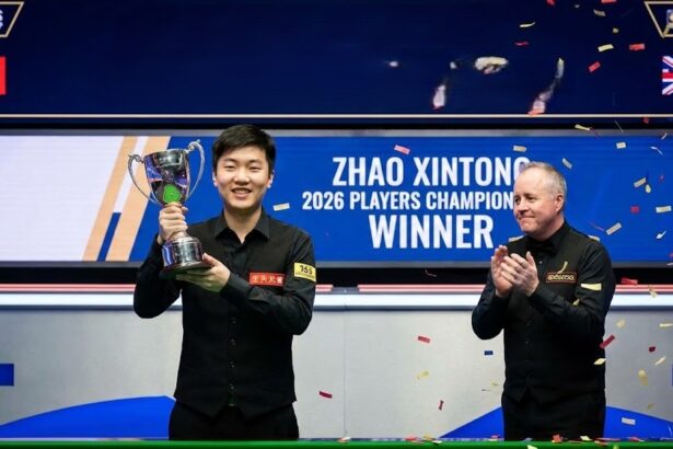 Snooker champion Zhao Xintong intensely lining up a shot on the billiard table during a professional match.