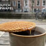 A fresh, golden-brown Dutch stroopwafel being pulled apart to reveal the gooey caramel center.