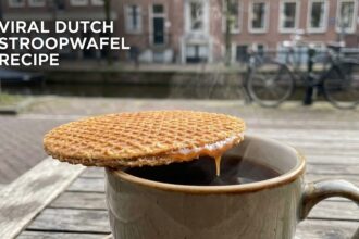 A fresh, golden-brown Dutch stroopwafel being pulled apart to reveal the gooey caramel center.