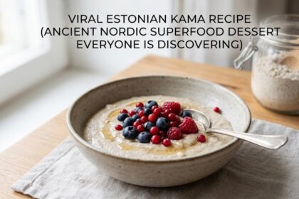 A glass bowl filled with Estonian Kama mixture topped with fresh blueberries and raspberries on a wooden table.
