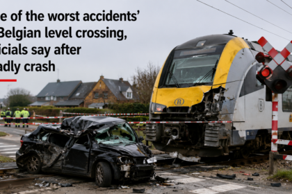 Emergency services surrounding the wreckage of a school minibus next to a railway line after a fatal train collision in Buggenhout, Belgium.